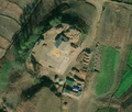 2/6 Cour de ferme (landuse=farmyard) entourée d'une clôture parsemée des tas de foins, reliée à la route (imagerie satellite Maxar).